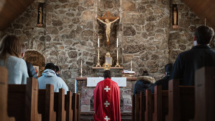 Sacerdote de arrodilla frente al altar durante una misa católica