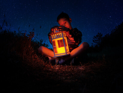 Niño observa hipnotizado la luz interno de una lámpara en medio de la noche