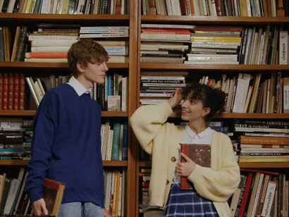 In the library's quiet corner, two students discuss how a reformed educational approach could better equip future leaders to tackle humanity's greatest challenges