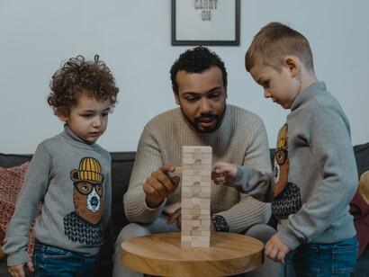 A imagem mostra uma cena edificante: um pai envolvido com seus filhos em um jogo de resiliência, destacando a importância da interação familiar no aprendizado