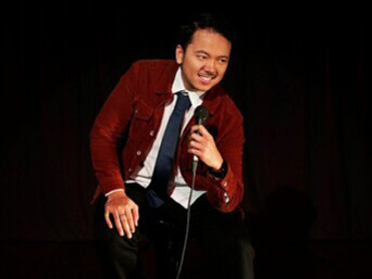 A comedian delivering a stand-up routine on stage, engaging the audience in a vibrant comedy club setting