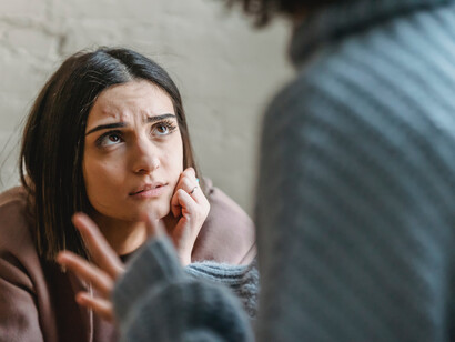 A woman stares sadly at her partner breaking up with her