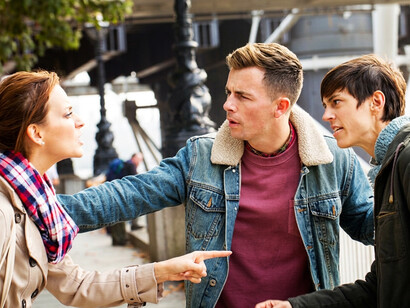 A young man tries to mediate a tense argument between two people who disagree over politics