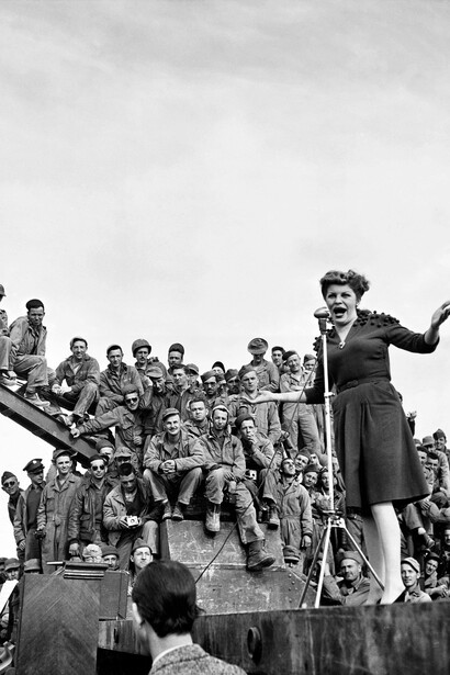 Margaret Bourke-White, Martha Raye si esibisce per le truppe. La comica e cantante americana si esibisce per un pubblico di soldati connazionali durante una tournée dell’USO per le truppe ancora di stanza nel Nord Africa durante la Seconda Guerra Mondiale. Nord Africa, 1943. Per gentile concessione di Margaret Bourke-White/The Life Picture Collection/Shutterstock