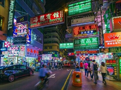 A Hong Kong street illuminated by colourful neon lights and bustling traffic, symbolising the city’s dynamic pace and constant movement