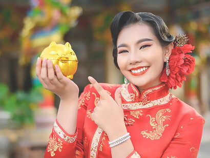 Experience the charm of traditional Lunar New Year festivities with a cheerful portrait of an Asian woman in elegant attire, surrounded by festive decorations