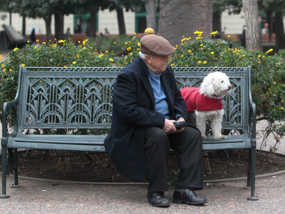 Un anciano sentado en el parque con su perro