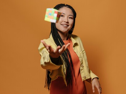 A woman throwing an unsolved Rubik's cube, symbolising the balance between mental growth and personal wellbeing
