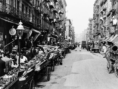 A bustling scene on Mulberry Street in New York City's Little Italy, filled with market stalls, shoppers, and members of the Italian-American community