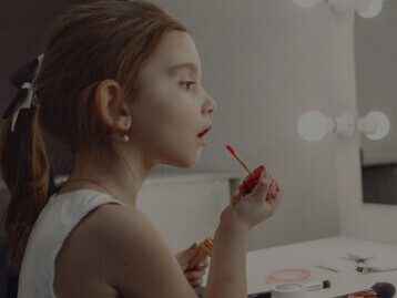 A little girl, wearing makeup and recording a video at home,  concerns about children and beauty products, the use of cosmetics by young girls, and issues related to childhood self-image