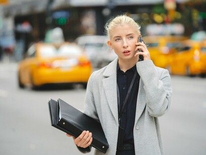 Mulher executiva fala no celular enquanto atravessa a rua