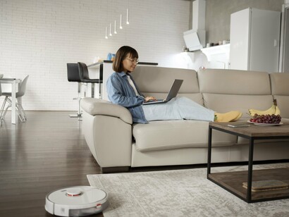 A resident working as a robot vacuum tidies the room, highlighting the evolution of everyday domestic comfort