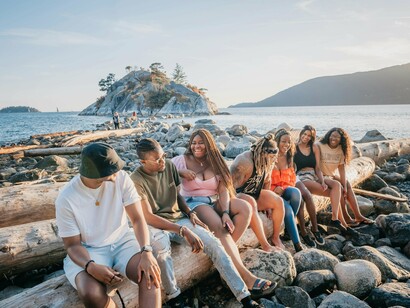 Friends sitting together under warm sunlight near the ocean, reflecting the peace found in companionship during difficult times