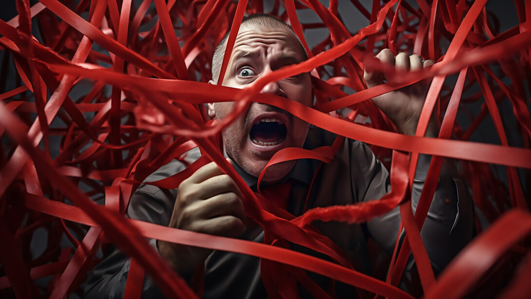 A person visibly anxious, tangled in a mess of cables and wires, symbolizing the overwhelming stress and chaos that can contribute to feelings of anxiety in the workplace