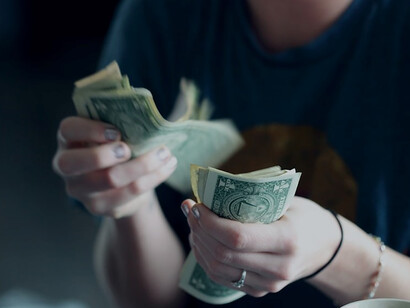 An individual holds a fan of U.S. dollar banknotes, illustrating a tangible connection to financial wealth and currency