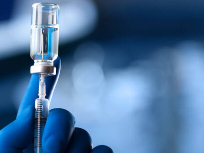 A healthcare worker, wearing a protective glove, carefully holds a vaccine ampoule and syringe, highlighting the critical role of vaccinations in safeguarding public health