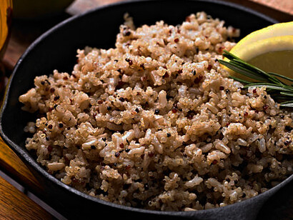 A beautifully arranged quinoa bowl brimming with colorful vegetables, served on a dark wooden rustic background
