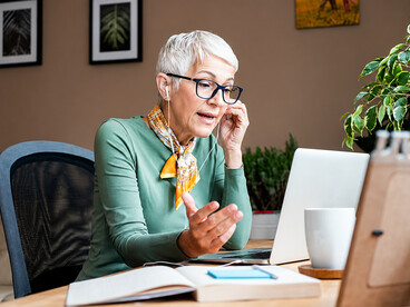An older woman using a laptop for remote office work in a comfortable home workspace