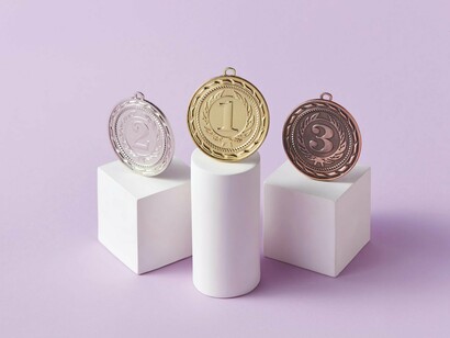 Neatly arranged gold, silver, and bronze medals on stands, symbolising the obsession with ranking and results