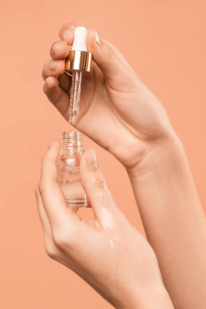 Person holding a serum bottle as part of a skincare and beauty routine
