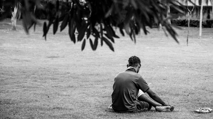 Homem sentado ao chão, desolado. A tristeza que pode ser causada por distorções da sociedade