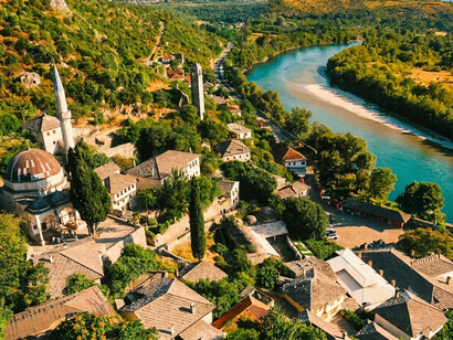 The Osum River curving alongside the historic neighborhoods and green hills, representing the scenic landscape of Berat, Albania