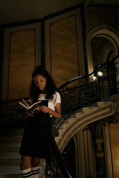 A woman stood on a staircase reading a book 