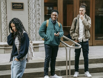 Un par de hombres maltratando a una chica que agarra sus pertenencias para cubrirse y baja la vista, asustada