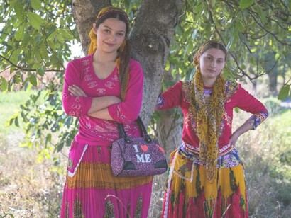 Young girls of the Roma group are leaning against a tree
