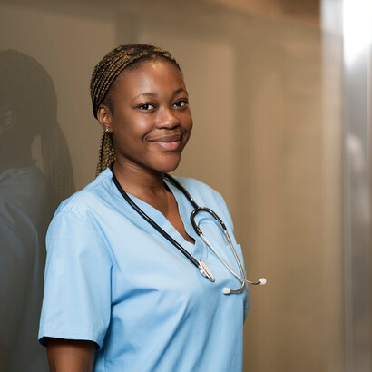 A portrait of a nurse in scrubs, set against the backdrop of a modern, elegantly designed clinic