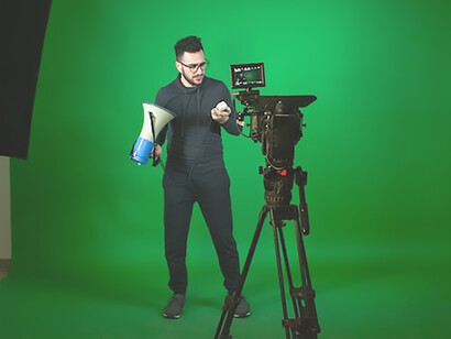An individual confidently addresses the camera, holding a microphone, while a green screen provides an adaptable backdrop, setting the stage for a dynamic and engaging filming session