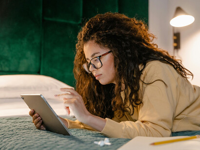 Woman lying comfortably on her bed, writing in her notebook