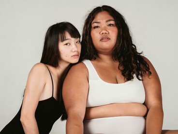 An Asian gay couple sharing an embrace on a simple gray backdrop