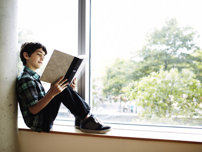 Un niño lee junto a la ventana