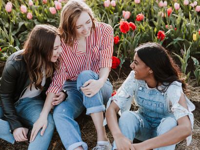 Three friends laughing together while surrounded by a field of tulips