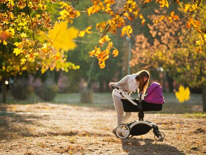 A woman leans over the stroller to check on the baby