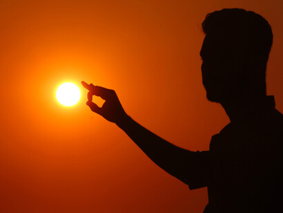 Perto da mão direita o sol se afunda a lua vermelha