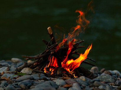 A small campfire lit among river rocks, reflecting the quiet moments where life's greatest lessons are shared