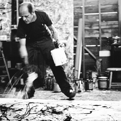 Jackson Pollock far colare il colore sulla tela disposta orizzontalmente