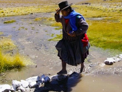 Una mujer indígena cruza en el cauce del Silala