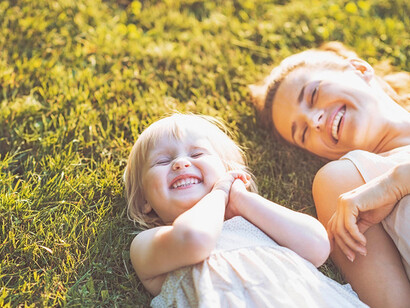 Mamma con figlia su un prato. Tra passeggini e seggioloni oggigiorno le mamme umane non tengono più, o tengono molto poco, i loro figli in braccio