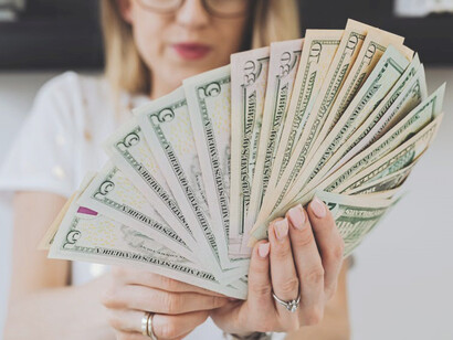 A woman holding a substantial stack of money in her hand