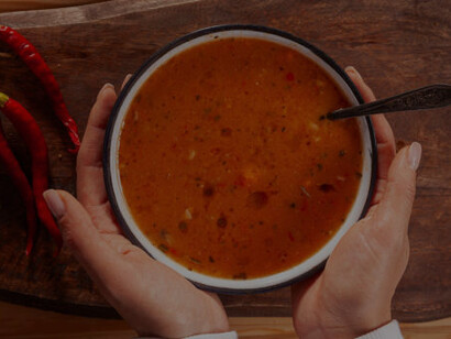 A woman relishes tarhana soup, beautifully displayed on a handcrafted wooden tray