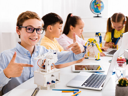 A group of young learners explores robotics and engineering while displaying their creative inventions in a vibrant classroom