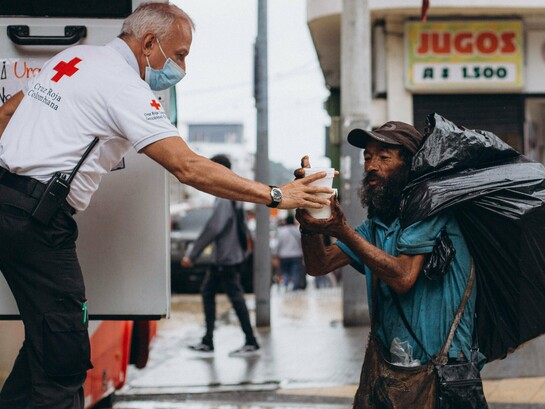 A humanitarian worker providing food assistance to a homeless man, representing efforts to uphold the right to food