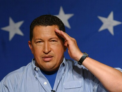 Hugo Chávez hace el saludo militar ante una bandera de Venezuela