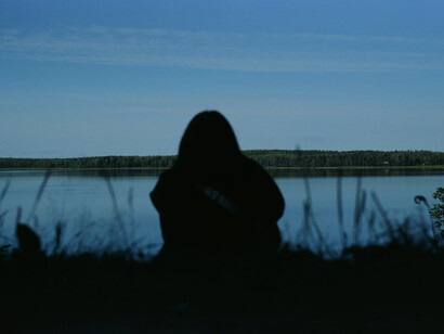Person sola davanti un lago al crepuscolo