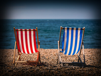 Dos tumbonas de tela mirando hacia la orilla del mar