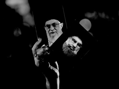 Una mujer sostiene las fotografías del líder supremo de Irán, Jamenei, y de Nasrallah, principal dirigente de Hezbollah