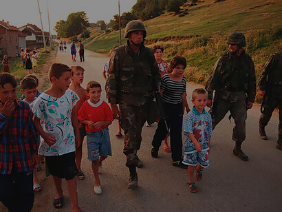 Gunnery Sgt. William Post marches with local children in Zegra, Kosovo, on June 28, 1999, as part of Operation Joint Guardian, a peacekeeping mission led by NATO forces in Kosovo